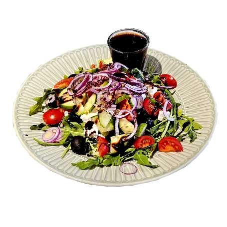 Bunter Salat mit Tomaten, Gurken, Zwiebeln und einem kleinen Glas Dressing.